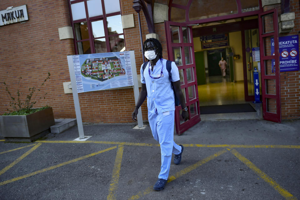 Mbaye Baacar Diouf, 33 dressed in his nurse's uniform walks, at Basurto hospital, in Bilbao, northern Spain, Wednesday, Nov. 18, 2020. Mbaye Babacar Diouf's life as a migrant in Europe took a turn for the better when he was adopted in Spain at the age of 28. That enabled him to pay his debts to human traffickers, study nursing and find a job at a Spanish hospital. Now he's giving back to the community. In a Bilbao hospital he cares for COVID-19 patients. (AP Photo/Alvaro Barrientos)