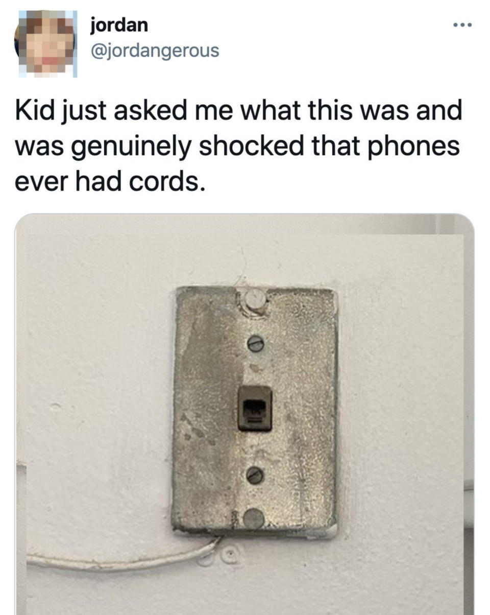 Tweet by @jordangerous reads: "Kid just asked me what this was and was genuinely shocked that phones ever had cords." Image shows a wall-mounted phone jack