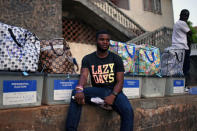 A man sits next to ballot boxes to be collected from a polling station during a presidential run-off in Freetown, Sierra Leone March 31, 2018. REUTERS/Olivia Acland