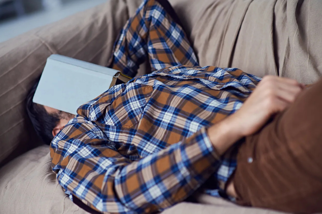 A middle-aged man naps on a couch.