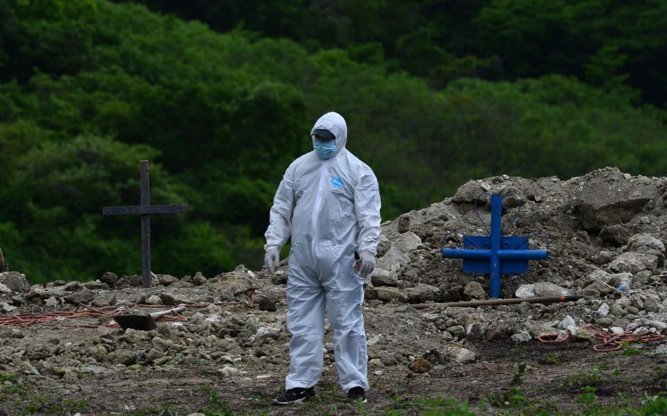 A man in a protective suit is pictured after burying a relative who died of Covid-19 on the outskirts of Tegucigalpa - AFP