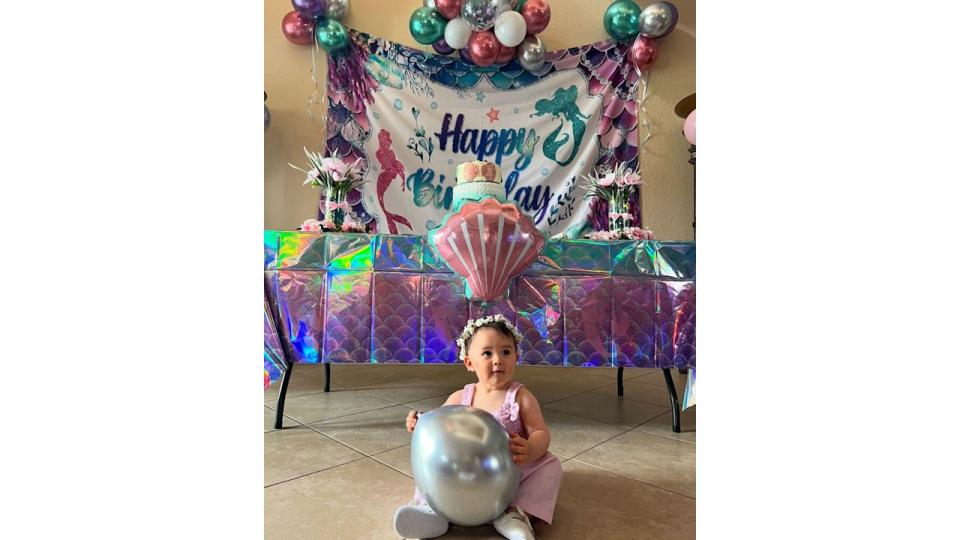 little girl sat on floor holding balloon 