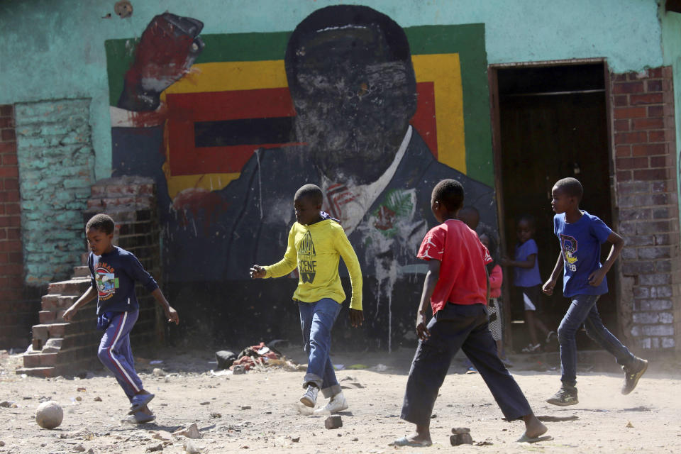 Children play soccer next to a defaced portrait of Former Zimbabwean President Robert Mugabe in Harare, Friday, Sept, 6 2019. Robert Mugabe, the former leader of Zimbabwe forced to resign in 2017 after a 37-year rule whose early promise was eroded by economic turmoil, disputed elections and human rights violations, has died. He was 95. (AP Photo/Tsvangirayi Mukwazhi)