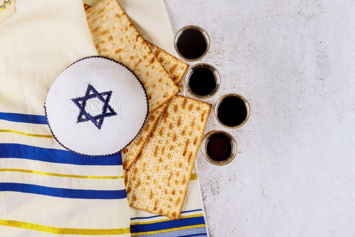 matzah and 4 glasses of red glasses of red wine for passover seder meal, prayer shawl, white yamaka with blue jewish star