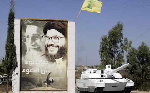 A French UN peacekeepers Leclerc tank passes a billboard showing Iran's supreme leader Ayatollah Ali Khamenei, left, and Hizbollah leader Hassan Nasrallah, right, on the road of the southern village of Borj Qalaway in Lebanon - Credit: AP