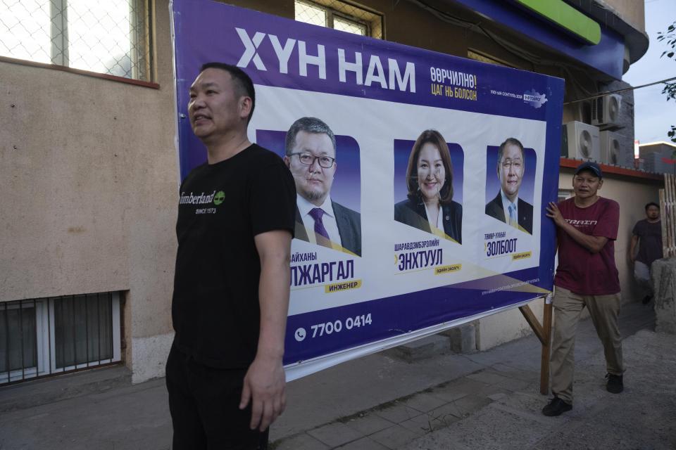 FILE- Workers remove publicity poster two days before polls open in Ulaanbaatar, Mongolia on June 26, 2024. Even in a busy year of elections, the next few days stand out. Voters go to the polls over the next week in fledgling democracies like Mauritania and Mongolia, in the Islamic Republic of Iran and in the stalwart democracies of Britain and France. (AP Photo/Ng Han Guan, File)