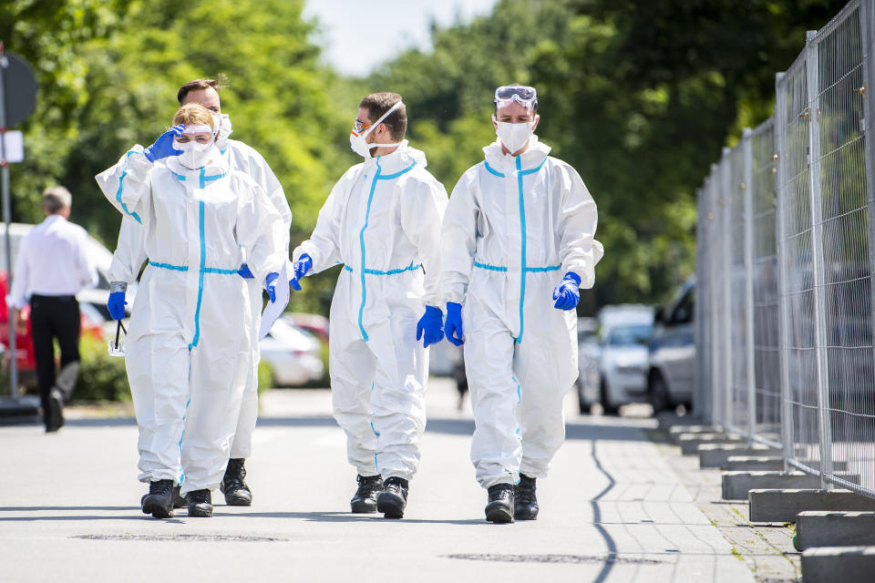 21 June 2020, North Rhine-Westphalia, Verl: Bundeswehr soldiers in protective suits and wearing mouth-and-nose masks go to the homes to test more people for the coronavirus. Following positive corona tests, the city of Verl has set up a quarantine for numerous Tönnies employees in the Sürenheide district. Several apartment buildings in which Tönnies' contract workers live have been quarantined. A total of almost 670 people live in the three streets affected. Photo: David Inderlied/dpa (Photo by David Inderlied/picture alliance via Getty Images)