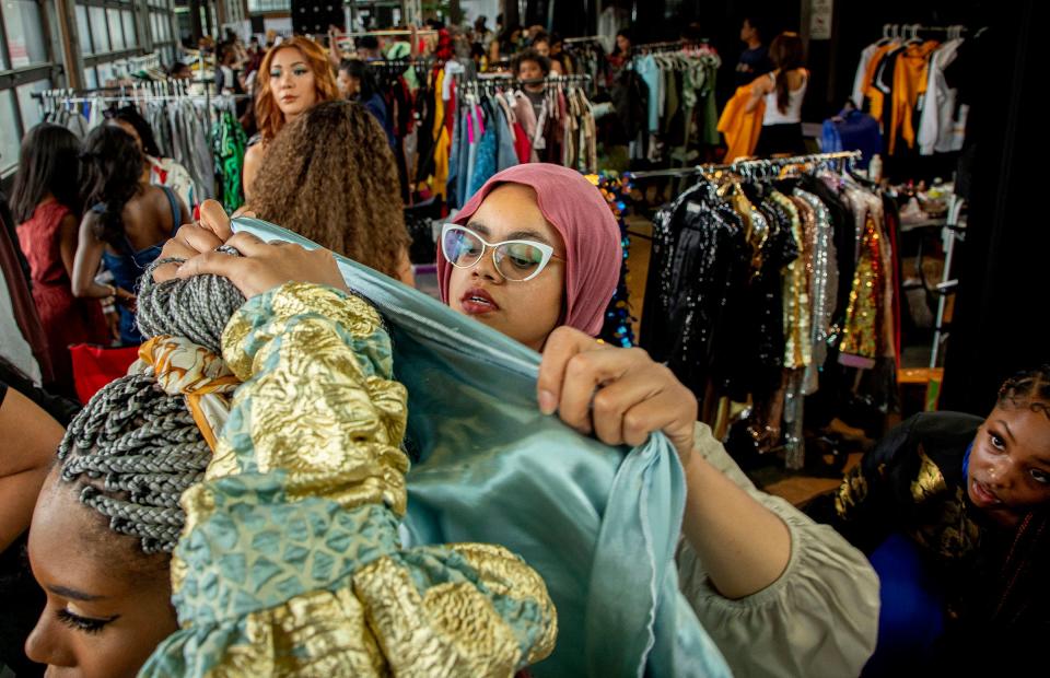 Designer LaTerry Moshin, of Sew Modest Studio, right, puts the finishing touches on the outfit she designed which is being worn by model Fai Marie as they prepare to walk the runway for the Michigan Fashion Week's 10th anniversary show at Eastern Market on June 10, 2022.