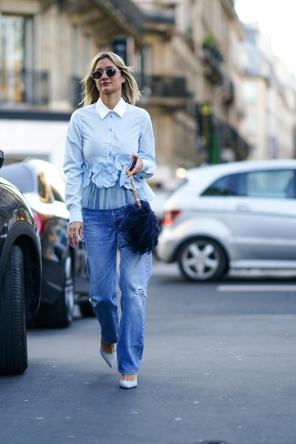 PARIS, FRANCE - JANUARY 22: Anne-Laure Mais wears sunglasses, a light blue ruffled shirt with a white collar and flowers embroidered, blue ripped jeans, light blue pointy pumps, a bag decorated with navy-blue feathers, outside Viktor & Rolf, during Paris Fashion Week - Haute Couture Spring/Summer 2020, on January 22, 2020 in Paris, France. (Photo by Edward Berthelot/Getty Images )