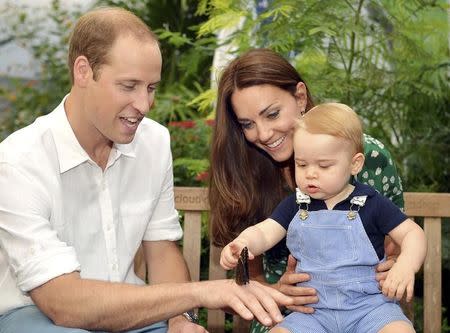 Britain's Catherine, Duchess of Cambridge, carries her son Prince George as he examines a butterfly on the hand of his father Prince William during a visit to the Sensational Butterflies exhibition at the Natural History Museum in London, July 2, 2014. REUTERS/John Stillwell/Pool