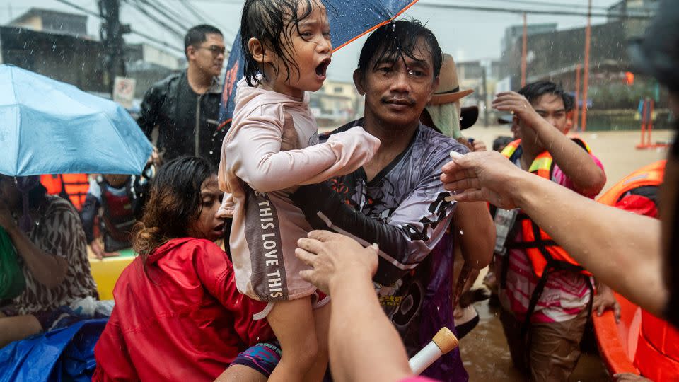 Rescuers assist a child getting off a boat along a flooded road following heavy rains brought by Typhoon Gaemi, in Marikina City, Metro Manila, Philippines, on July 24, 2024. - Lisa Marie David/Reuters