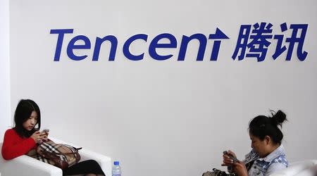 Visitors use their smarts phones underneath the logo of Tencent at the Global Mobile Internet Conference in Beijing May 6, 2014. REUTERS/Kim Kyung-Hoon