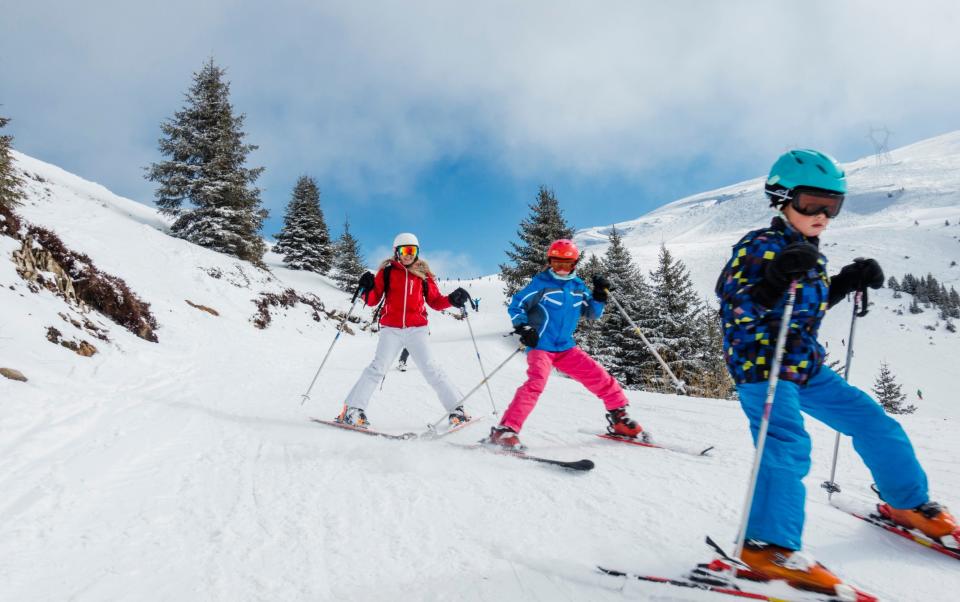 Three family members go down a ski slope at high speed