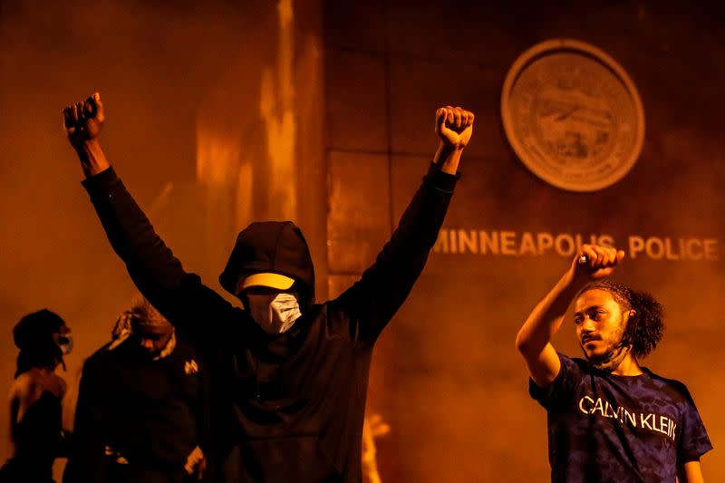Protesters react after setting fire to the entrance of a police station as demonstrations continue in Minneapolis