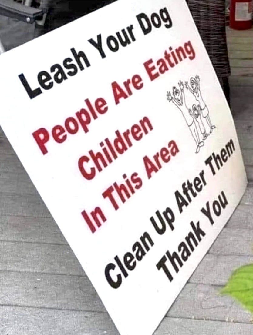 A sign that says "leash your dog people are eating children in this area clean up after them thank you"