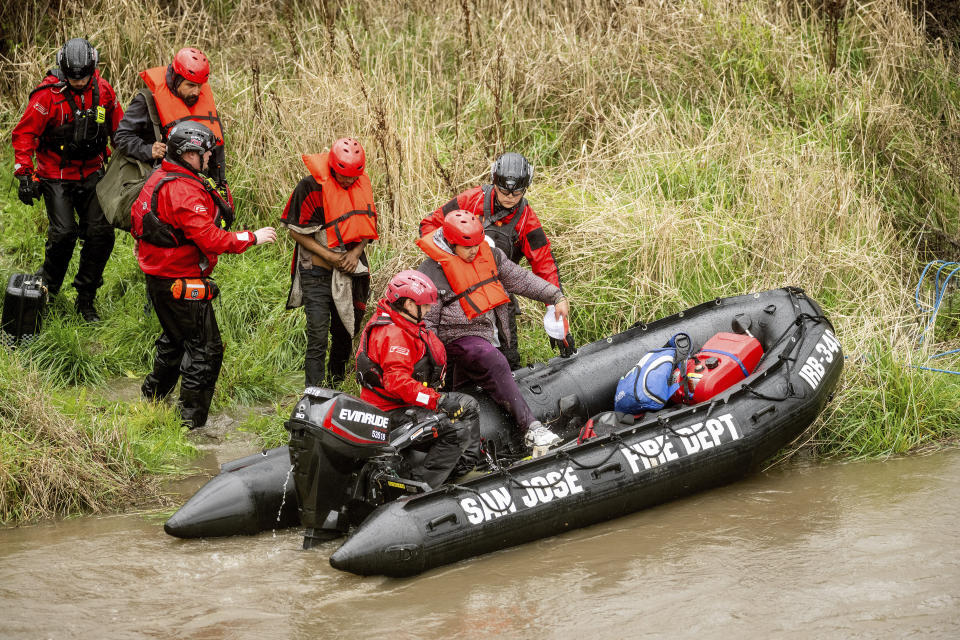 Search and rescue workers evacuate men from a homeless encampment that became surrounded by floodwater from the Guadalupe River on Sunday, Feb. 4, 2024, in San Jose, Calif. (AP Photo/Noah Berger)