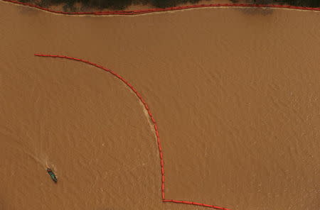 A boat is pictured near the Rio Doce (Doce River), which was flooded with mud after a dam owned by Vale SA and BHP Billiton Ltd burst, at an area where the river joins the sea on the coast of Espirito Santo in Regencia Village, Brazil, November 23, 2015. REUTERS/Ricardo Moraes