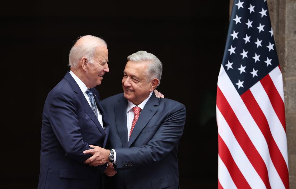 President Joe Biden and Mexican President Andrés Manuel López Obrador shaking hands while standing in front of an American flag.