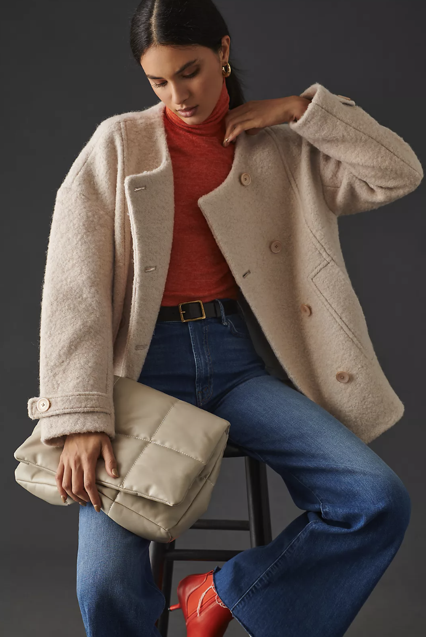 woman wearing blue jeans, red sweater and white Maeve Bouclé Coat (Photo via Anthropologie)