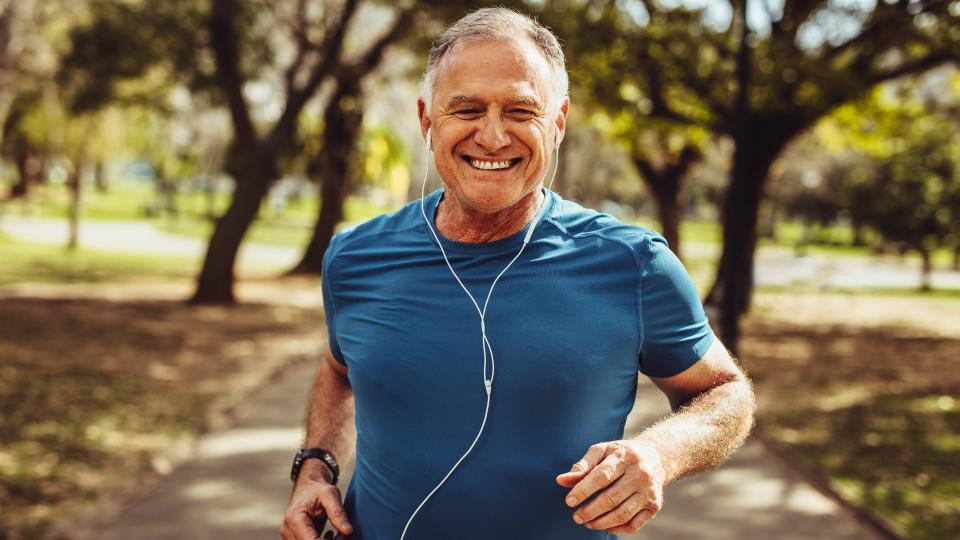 Portrait of a senior man in fitness wear running in a park.