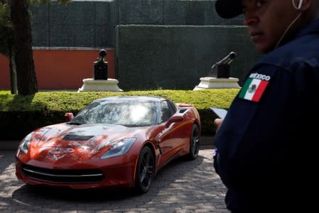 A police officer stands near a Chevrolet Corvette Stingray, 2015 part of the fleet of vehicles seized by the government from politicians and organized crime as part of an auction in Mexico City