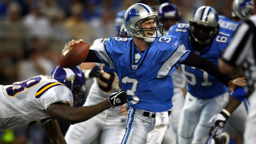 Joey Harrington tries to throw a pass while being pulled down by a Minnesota defender.