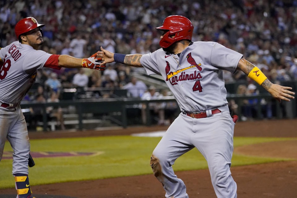 St. Louis Cardinals' Yadier Molina (4) greets teammate Nolan Arenado after scoring on an RBI single by Paul Goldschmidt during the seventh inning of a baseball game against the Arizona Diamondbacks, Friday, Aug. 19, 2022, in Phoenix. (AP Photo/Matt York)