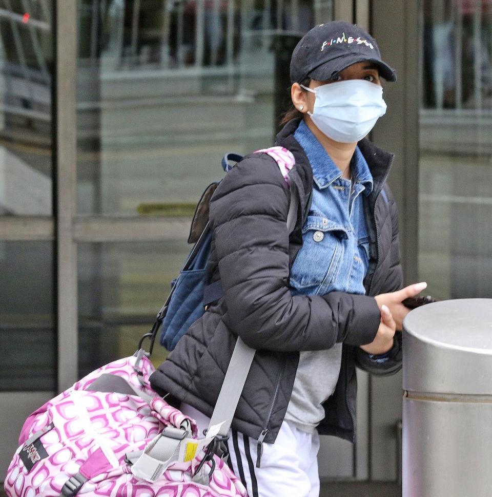 Stephanie Spencer 25 of Newark waits for a ride after arriving at Newark Airport. She wore a mask on the plane to protect herself from germs and the Corona Virus. She says that she is naturally conscious of germs due to living with younger siblings. Several passengers this afternoon arriving in Terminal B at Newark Airport were trying to protect themselves from the spread of the Corona Virus.