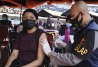 A woman receives a shot of the Sinovac COVID-19 vaccine during a mass vaccination at a soccer stadium in Bandung, West Java, Indonesia, Thursday, June 17, 2021. Indonesia's president ordered authorities to speed up the country's vaccination campaign as the World Health Organization warned Thursday of the need to increase social restrictions in the country amid a fresh surge of coronavirus infections caused by worrisome variants. (AP Photo/Bukbis Candra)