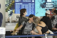 A couple kisses while waiting in line to check-in at the Delta booth on Wednesday, Nov. 22, 2023, at Los Angeles International Airport. The late crush of holiday travelers is picking up steam, with about 2.7 million people expected to board flights on Wednesday and millions more planning to drive or take the train to Thanksgiving celebrations. (AP Photo/Damian Dovarganes)