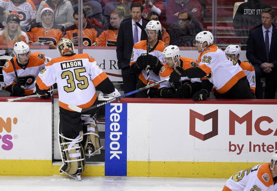 Philadelphia Flyers goalie Steve Mason (35) gets a tap from the stick of right wing Dale Weise (22) as he steps into the bench area after he was pulled during the third period of an NHL hockey game against the Washington Capitals, Sunday, Jan. 15, 2017, in Washington. (AP Photo/Nick Wass)