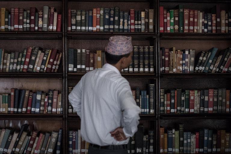 An employee checks the bookshelves at the damaged Kaiser Library in Kathmandu on May 7, 2015