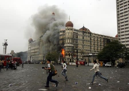 Photographers run past burning Taj Mahal Hotel during a gun battle in Mumbai November 29, 2008. REUTERS/Arko Datta