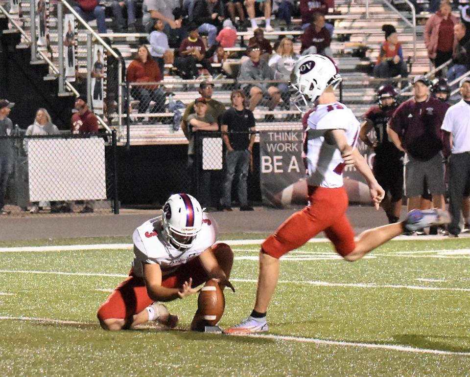 Connor Wardlaw kicks the ball through the uprights for the extra point while Brody Lester holds.