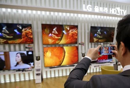 An employee takes photographs of LG Electronics' organic light-emitting diode (OLED) TV sets, which are made with LG Display flat screens, at its store in Seoul January 28, 2015. REUTERS/Kim Hong-Ji/File Photo