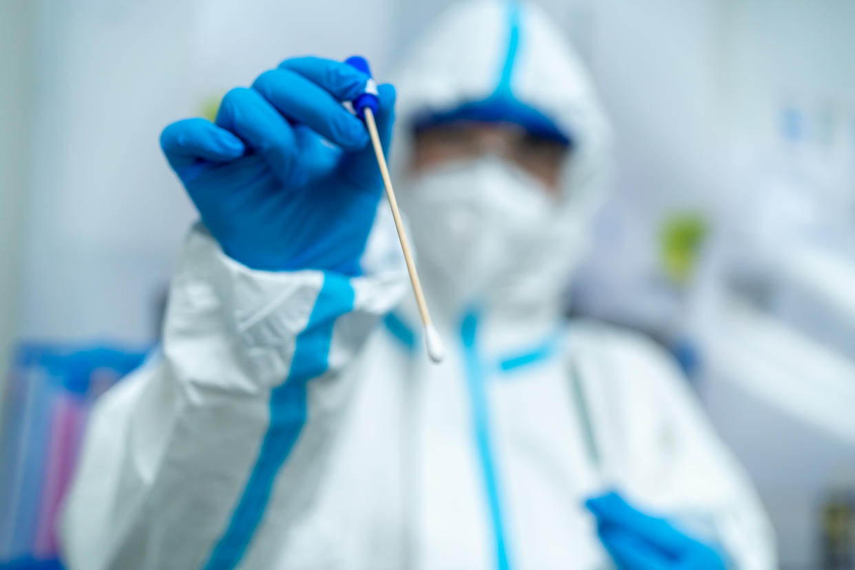 An Asian female doctor holds a throat swab