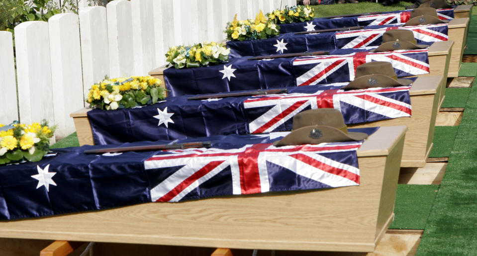 FILE - In this Thursday, Oct. 4, 2007 file photo, the flag draped coffins of five Australian soldiers, including John "Jack" Hunter, await re-burial during a ceremony at Buttes Military Cemetery in Zonnebeke, Belgium. On another Anzac Day turned lonesome by the global pandemic, solitary actions show all the more how the sacrifices of Australia and New Zealand during World War I are far from forgotten. While global attention will turn at dawn on Sunday to the beaches of Turkey’s Gallipoli where the two emerging countries crafted a sense of nationhood from the horrors of war in April 1915, all along the front line in Europe, small ceremonies will show gratitude over a century after the war ended. (AP Photo/Virginia Mayo, File)