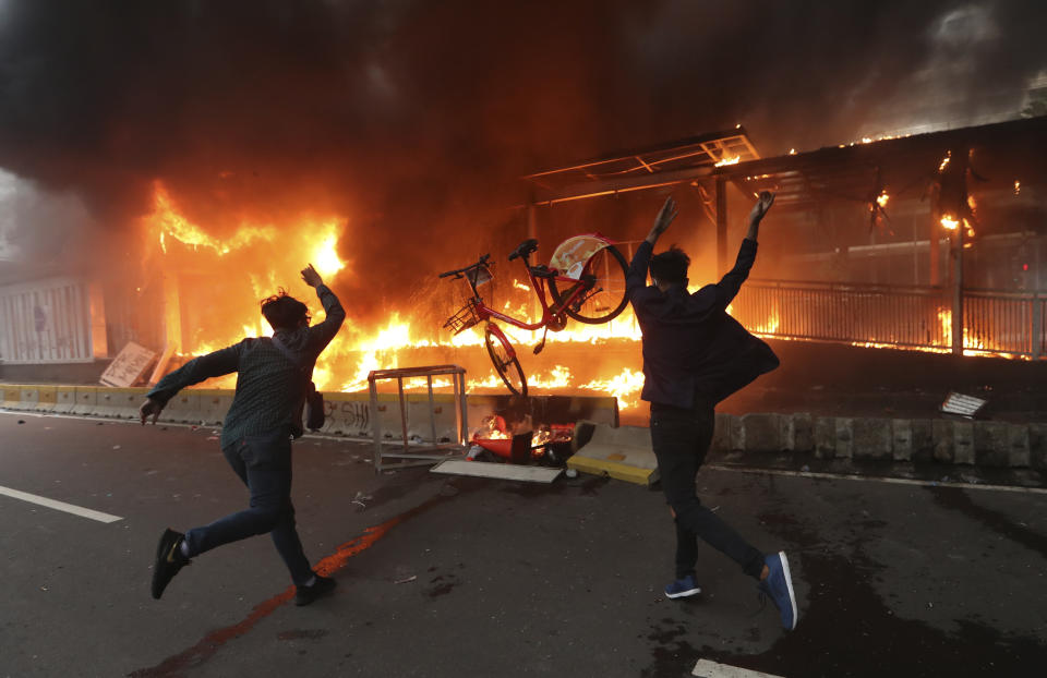 Protesters add a bicycle to a burning metro station during a rally in Jakarta, Indonesia, Thursday, Oct. 8, 2020. Thousands of enraged students and workers staged rallies across Indonesia on Thursday in opposition to a new law they say will cripple labor rights and harm the environment. (AP Photo/Achmad Ibrahim)