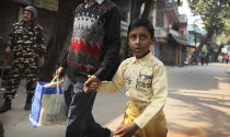 A child looks at an Indian paramilitary soldier standing guard after Tuesday's violence in New Delhi, India, Wednesday, Feb. 26, 2020. At least 20 people were killed in three days of clashes in New Delhi, with the death toll expected to rise as hospitals were overflowed with dozens of injured people, authorities said Wednesday. The clashes between Hindu mobs and Muslims protesting a contentious new citizenship law that fast-tracks naturalization for foreign-born religious minorities of all major faiths in South Asia except Islam escalated Tuesday. (AP Photo/Manish Swarup)