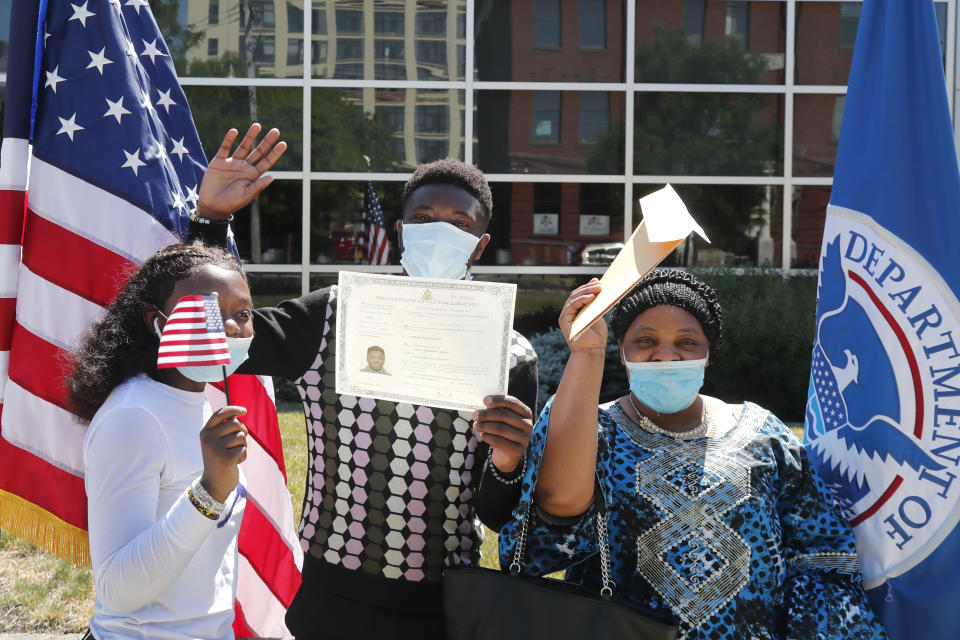 RETRANSMISSION TO CORRECT NAME TO ALBERT BARAKA - Albert Baraka, middle, celebrates his new citizenship with his sister, Delice, left, and his mother, Florence after ceremonies, Thursday, June 4, 2020, in Lawrence, Mass. The federal agency charged with overseeing legal immigration and citizenship is resuming services in many cities across the country after being shuttered for more than two months because of the coronavirus pandemic. (AP Photo/Elise Amendola)