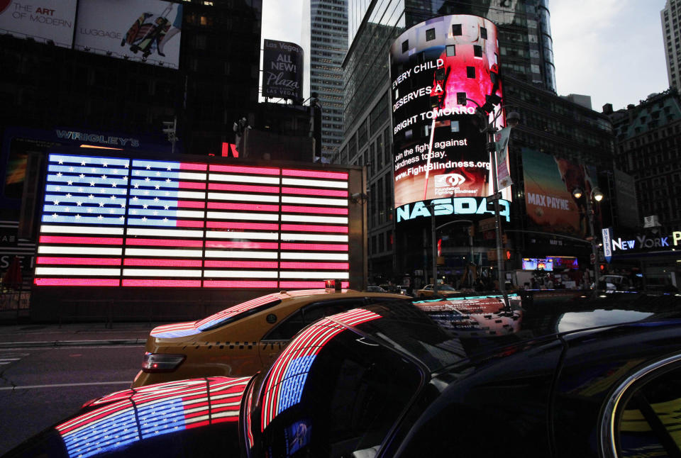 FILE - A neon American flag hangs on the side of the Armed Forces Recruiting Station, seen at left, in New York's Times Square, May 17, 2012. Flags proliferate every July Fourth, but it wasn't always a revered and debated symbol. Unlike the right to assemble or trial by jury, the flag's role was not prescribed by the founders: Flags would have been rare during early Independence Day celebrations and were so peripheral to early U.S. history that no original flag exists. (AP Photo/Mark Lennihan, File)