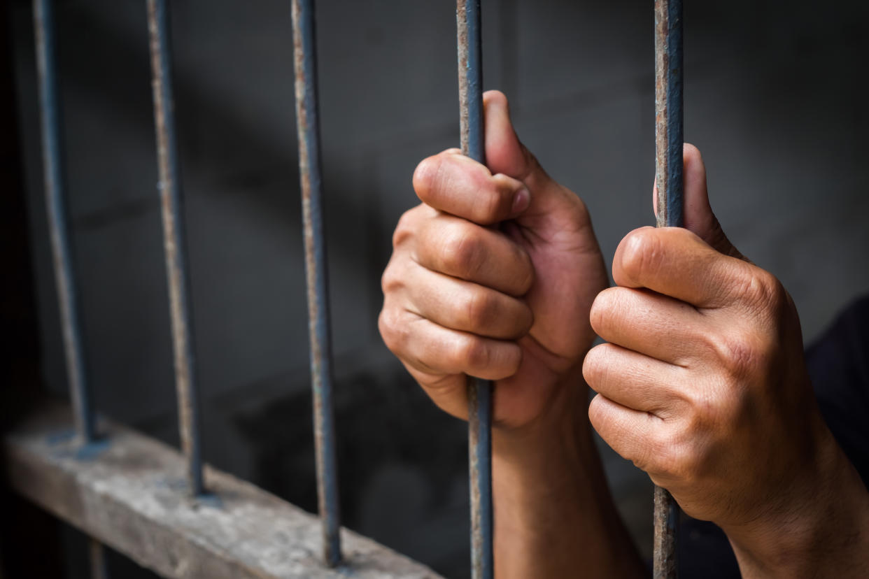 Hands of man behind jail bars. (Photo: Getty Images)