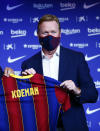 Ronald Koeman holds up a soccer shirt with his name on it during his official presentation as coach for FC Barcelona in Barcelona, Spain, Wednesday, Aug. 19, 2020. Barcelona officially announced earlier on Wednesday a deal with Koeman to become their coach five days after the team's humiliating 8-2 loss to Bayern Munich in the Champions League quarterfinals. Barcelona says the former defender's deal runs through June 2022. Koeman replaces the fired Quique Setien. (AP Photo/Joan Monfort)