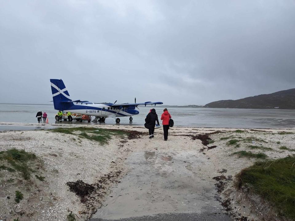 passengers walk towards a plane on a beach