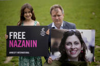 Richard Ratcliffe, the husband of imprisoned British-Iranian Nazanin Zaghari-Ratcliffe and their seven year old daughter Gabriella pose for the media backdropped by the scaffolded Houses of Parliament and the Elizabeth Tower, known as Big Ben, in Parliament Square, London, to mark the 2,000 days she has been detained in Iran, Thursday, Sept. 23, 2021. Zaghari-Ratcliffe was originally sentenced to five years in prison after being convicted of plotting the overthrow of Iran's government, a charge that she, her supporters and rights groups deny. While employed at the Thomson Reuters Foundation, the charitable arm of the news agency, she was taken into custody at the Tehran airport in April 2016 as she was returning home to Britain after visiting family. (AP Photo/Matt Dunham)