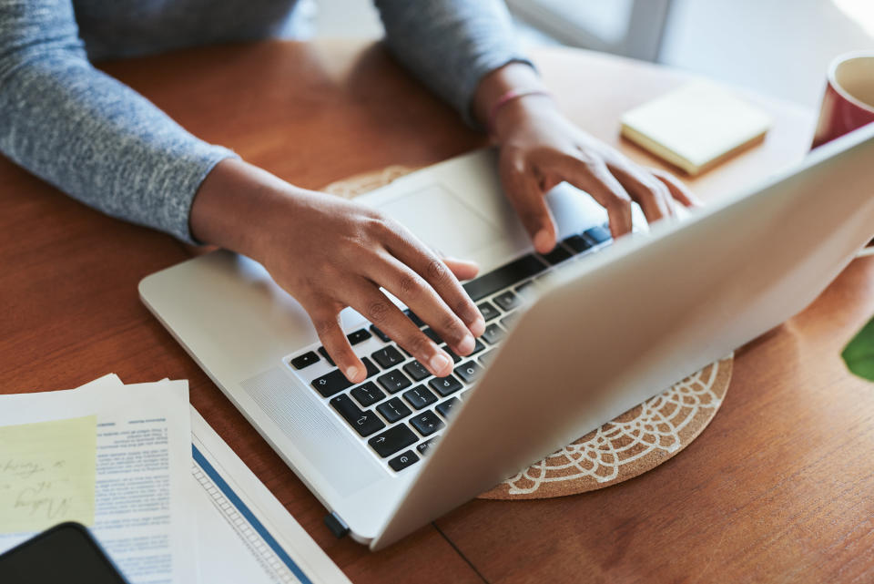 Hands typing on a laptop keyboard at a table