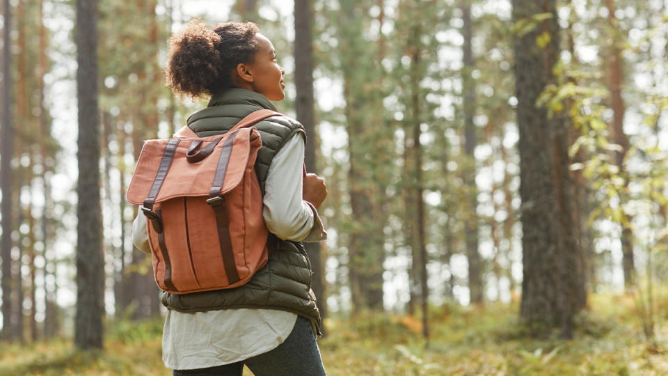 Woman rucking among trees with a weighted backpack