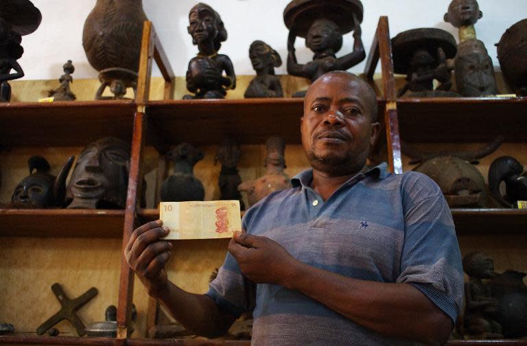 Museum guide Barthelemy Kayumba shows an old 10-Congolese-Franc banknote displaying the "Little Kabila", a statuette standing on the shelf behind him, at the Kivu Museum in Bukavu on March 17, 2015