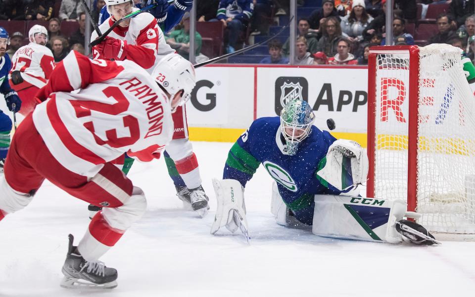 Vancouver Canucks goalie Thatcher Demko, right, stops a shot by Detroit Red Wings' Lucas Raymond (23) during the first period of an NHL hockey game Thursday, March 17, 2022, in Vancouver, British Columbia. (Darryl Dyck/The Canadian Press via AP)