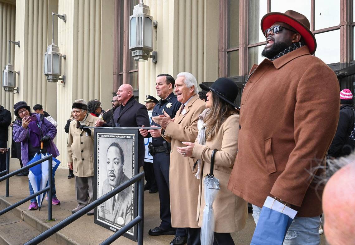 VIPs stand with a portrait of Rev. Martin Luther King Jr. as Pastor David J. Criner Jr., right, leads marchers in song at the conclusion of the 39th annual Martin Luther King Jr Day March at the Fresno Veterans Memorial Auditorium on Monday, Jan. 16, 2023.